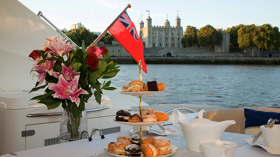Afternoon tea setup on a luxury yacht with Tower of London in the background